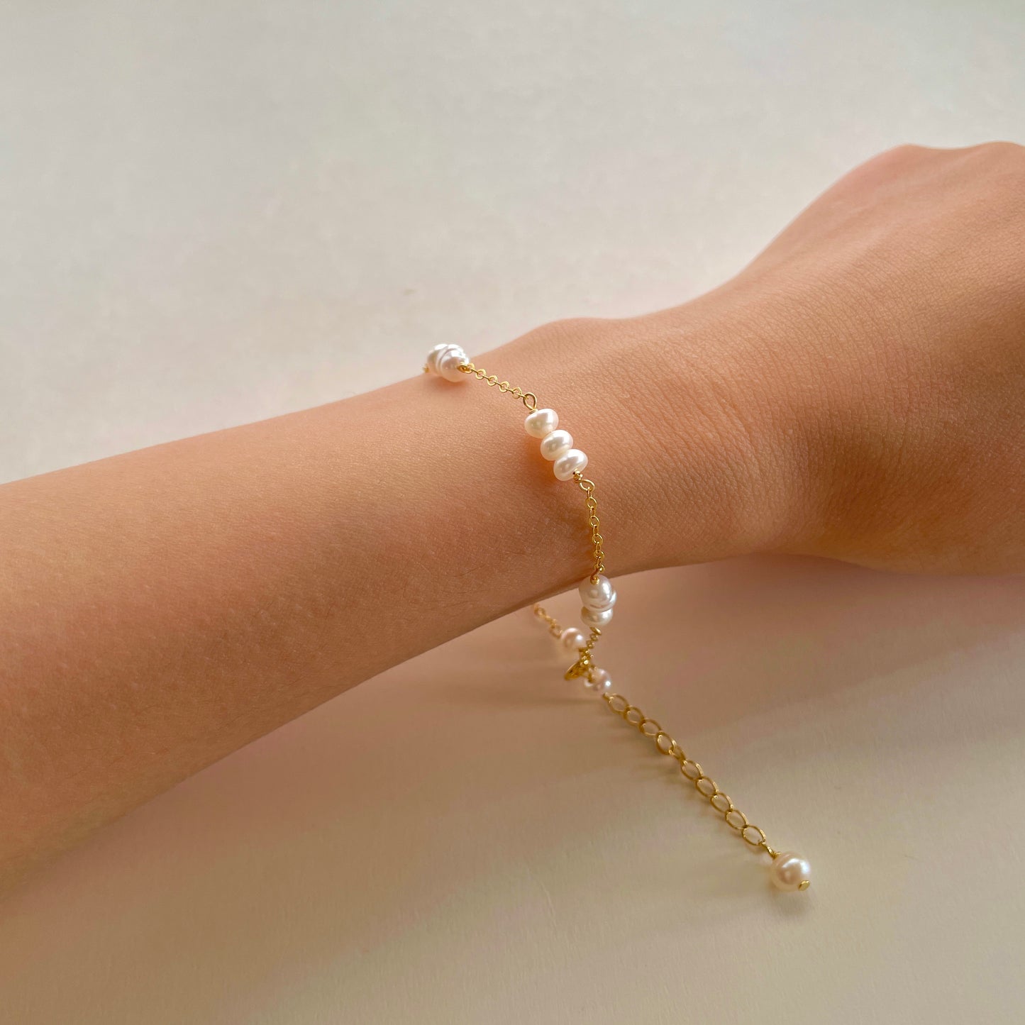 delicate pearl bracelet on a hand, with every three small pearls strung together， gold vermeil