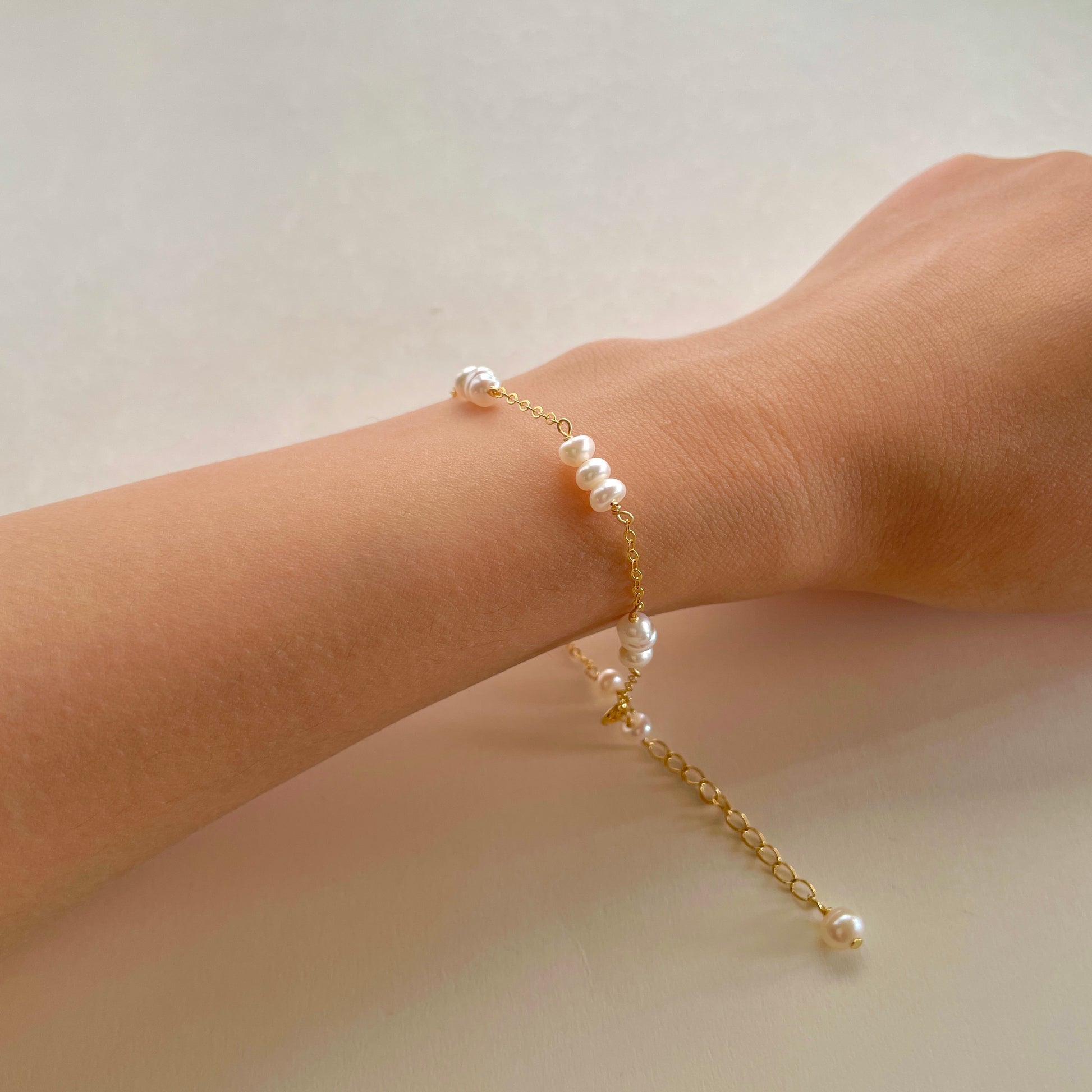 delicate pearl bracelet on a hand, with every three small pearls strung together， gold vermeil