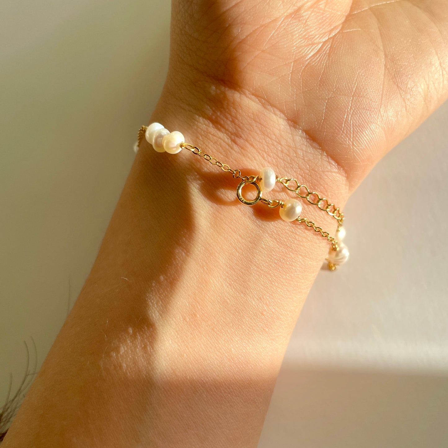 delicate pearl bracelet on a hand, with every three small pearls strung together， gold vermeil